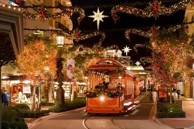 an orange trolley car driving down a street with christmas lights at High stay, new furniture apartment in Glendale