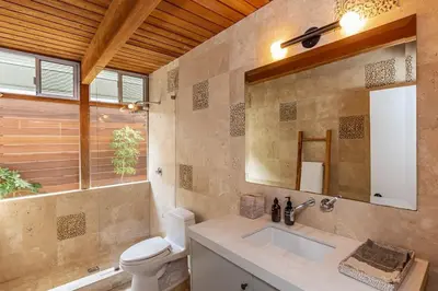 a bathroom with a sink and a toilet and a mirror at The Hideaway Beach House by Stay Awhile Villas in Malibu Beach