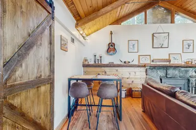 a barn door in a living room with a table and stools at Couples Retreat Near Lake Arrowhead and Hiking! in Lake Arrowhead