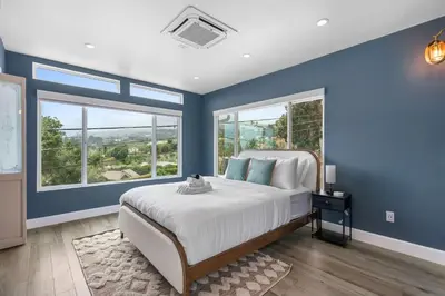 a blue bedroom with a large bed and two windows at New Listing Palisades Villa by Colby & Conrad in Los Angeles