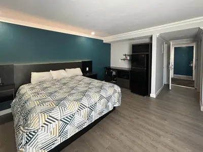 a bedroom with a bed and a blue wall at Studio 6 Suites Buena Park CA Anahiem Near Maingate Knotts in Buena Park