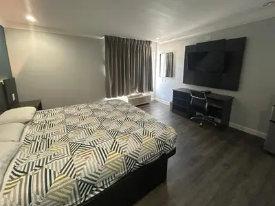 a bedroom with a bed and a flat screen tv at Studio 6 Suites Buena Park CA Anahiem Near Maingate Knotts in Buena Park