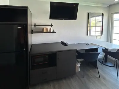 a kitchen with a black refrigerator and a table at Studio 6 Suites Buena Park CA Anahiem Near Maingate Knotts in Buena Park