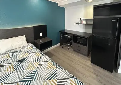 a hotel room with a bed and a desk at Studio 6 Suites Buena Park CA Anahiem Near Maingate Knotts in Buena Park