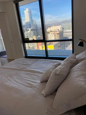 a bed with pillows in front of a large window at Luxury 1 Bedroom vacation Home in Downtown LA in Los Angeles