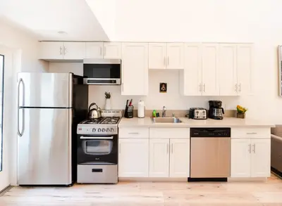 a kitchen with white cabinets and a stainless steel refrigerator at Modern 1-Bedromm Loft In Hollywood With Viwe of Hollywood Sign in Los Angeles