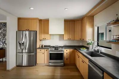 a kitchen with wooden cabinets and a stainless steel refrigerator at NEW! High-End Spanish Duplex | Luxury 3BR in Los Angeles