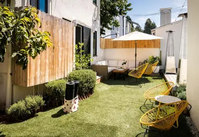 a backyard with grass and chairs and an umbrella at NEW! High-End Spanish Duplex | Luxury 3BR in Los Angeles