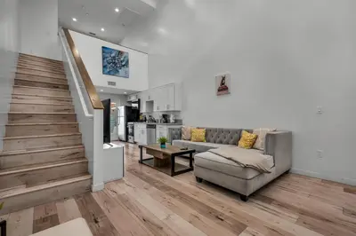 a living room with a couch and a staircase at Loft-Style 1-Bedroom Apartment with Balcony & Private Parking in Hollywood in Los Angeles