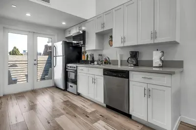 a kitchen with white cabinets and stainless steel appliances at Loft-Style 1-Bedroom Apartment with Balcony & Private Parking in Hollywood in Los Angeles