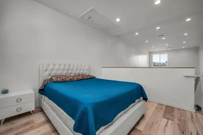a white bedroom with a bed with a blue blanket at Loft-Style 1-Bedroom Apartment with Balcony & Private Parking in Hollywood in Los Angeles