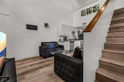 a living room with a staircase and a kitchen at Lux Hollywood Loft 1BR with Balcony & Private Parking 10 Min to Downtown LA in Los Angeles