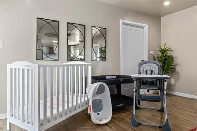 a nursery with a crib and a chair and mirrors at KingBeds Skylight 1GB Wi-Fi Step-free Clean in Bakersfield