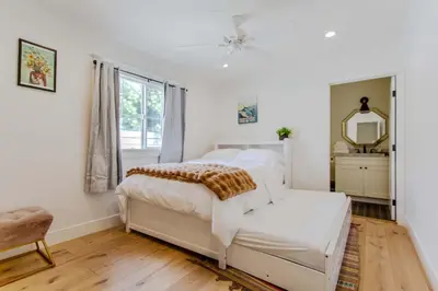 a white bedroom with a bed and a mirror at Spacious 4BR Games Workspace Outdoor Fun in Los Angeles