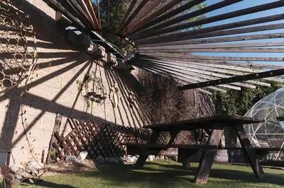 a wooden bench sitting next to a wall with a large fan at Mid-Century Modern Hillside Escape With Dome and Views in Los Angeles