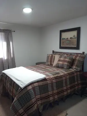 a bedroom with a bed with a plaid blanket at Mountain Top Barn retreat with View in Bodfish