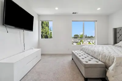 a white bedroom with a large bed and a flat screen tv at NoHo Modern Townhouse with Gorgeous Rooftop in Van Nuys