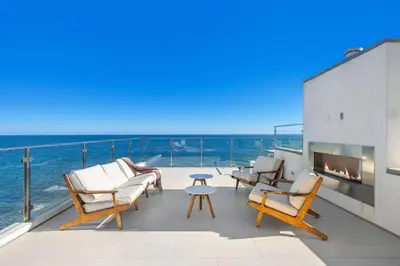 a patio with chairs and a fireplace and the ocean at Casa Mare by Stay Awhile Villas in Malibu Beach