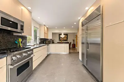 a large kitchen with white cabinets and a stainless steel refrigerator at Allura Studio City Mediterranean with Private Pool in Los Angeles