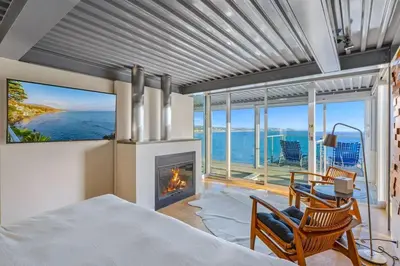 a bedroom with a bed and a fireplace and the ocean at Broad Beach Wdirect Beach Access in Malibu