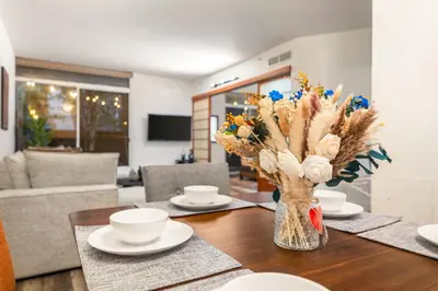 a dining room table with a vase of flowers on it at Spacious 2 Bedroom Condo in DTLA, Large Private Patio, Pets Welcomed in Los Angeles