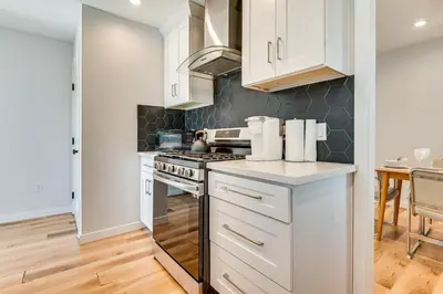a kitchen with white cabinets and a stove at 4 Mi to SoFi Stadium Modern Home with Fenced Yard in Los Angeles