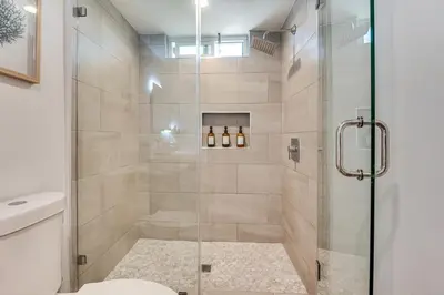a bathroom with a shower with a glass door at 4 Mi to SoFi Stadium Modern Home with Fenced Yard in Los Angeles