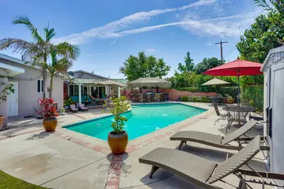 a swimming pool with chairs and a table and umbrella at Cozy Couples Oasis with Pool 3 Mi to Disneyland! in Garden Grove