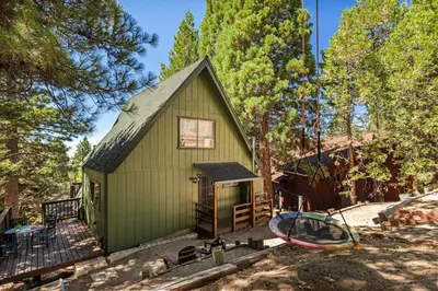 a green house with a surfboard in front of it at Casa Huntsted A-Frame Cabin near Snow Valley in Running Springs