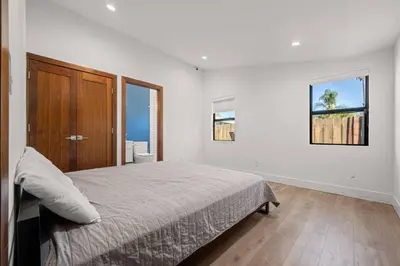 a white bedroom with a bed and two windows at Coulson Street Retreat with pool BBQ and more in Los Angeles