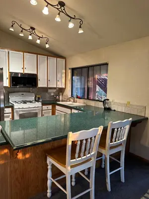 a kitchen with a large counter with two chairs at a table at Charming Pine Mountain Home with Family Space in Frazier Park