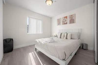 a white bedroom with a bed and a window at Niagara Haven in Burbank