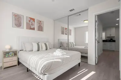 a white bedroom with a bed and a mirror at Niagara Haven in Burbank