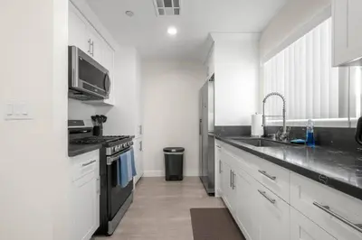 a white kitchen with a sink and a stove at Niagara Haven in Burbank