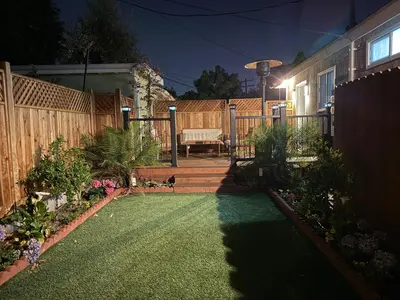 a backyard at night with a fence and a bench at Cheerful house with EV, Parking & backyard in Los Angeles