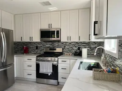 a kitchen with white cabinets and a stove top oven at Cheerful house with EV, Parking & backyard in Los Angeles