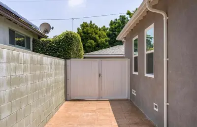 a fence with a white gate in front of a house at Modern Studio with Private Patio in Los Angeles