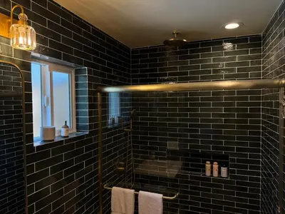 a black tiled bathroom with a shower and a window at The Garden Escape in Los Angeles