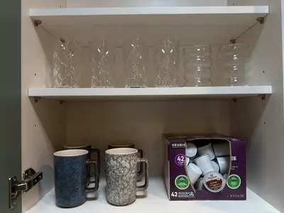 a cupboard with two mugs and a box and glasses at The Garden Escape in Los Angeles