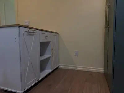an empty kitchen with white cabinets and a wooden floor at The Garden Escape in Los Angeles