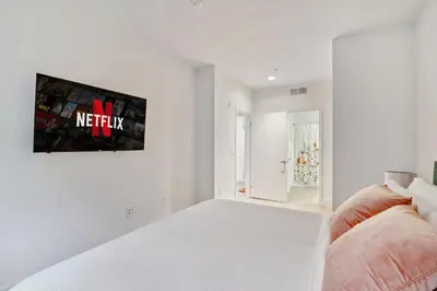 a white room with a bed and a tv on the wall at 2BR Coastal Retreat Walk to Beach, free parking in Los Angeles