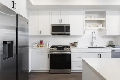 a white kitchen with a stove and a refrigerator at Noho Alexan Modern 2bed Duo with FREE Parking in Garnsey
