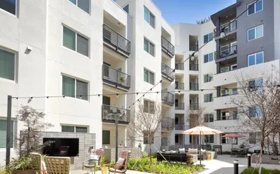 an apartment building with chairs and an umbrella at Noho Alexan Modern 2bed Duo with FREE Parking in Garnsey