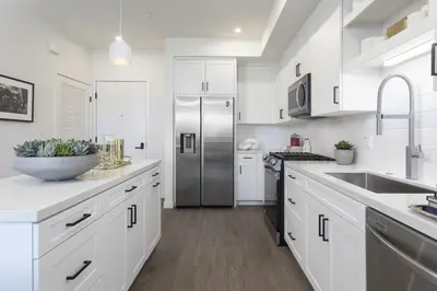 a kitchen with white cabinets and a stainless steel refrigerator at Noho Alexan Modern 2bed Duo with FREE Parking in Garnsey