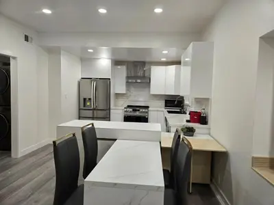 a kitchen with white cabinets and a table and chairs at Soft elegance, modern guest house in Alhambra