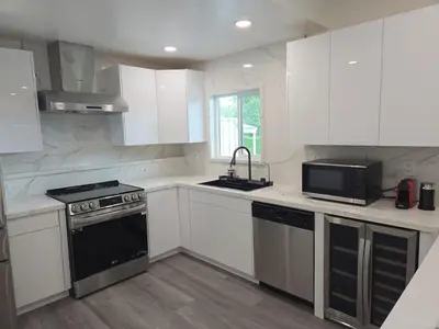a kitchen with white cabinets and a black stove top oven at Soft elegance, modern guest house in Alhambra