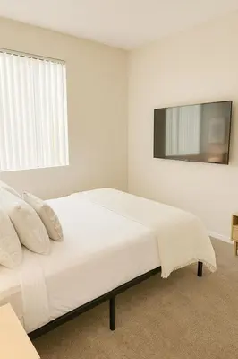 a white bedroom with a bed and a tv on the wall at Marina Del Rey Sunrise - Pool & Gym & Sauna & Cinema in Marina del Rey