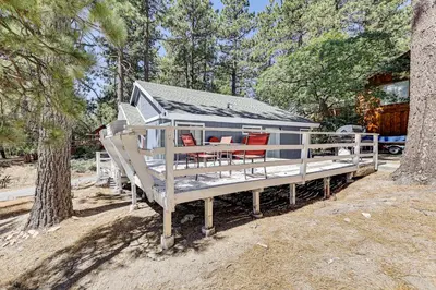 a blue house with red chairs on a porch at Swim, Ski and Explore Cabin in Green Valley Lake! in Green Valley Lake