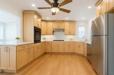 a kitchen with wooden cabinets and a ceiling fan at Fullerton Fairytale Vacation Home - 10 Min Drive to Disneyland in Fullerton