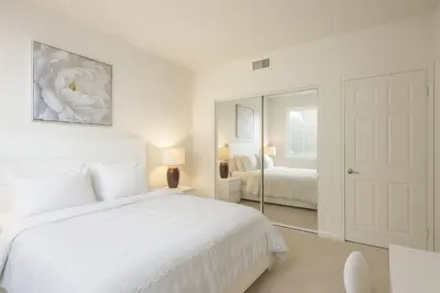 a white bedroom with a bed and a mirror at Marina del Rey Coastal 2BR Retreat- Pool, Hot Tub, Gym in Los Angeles